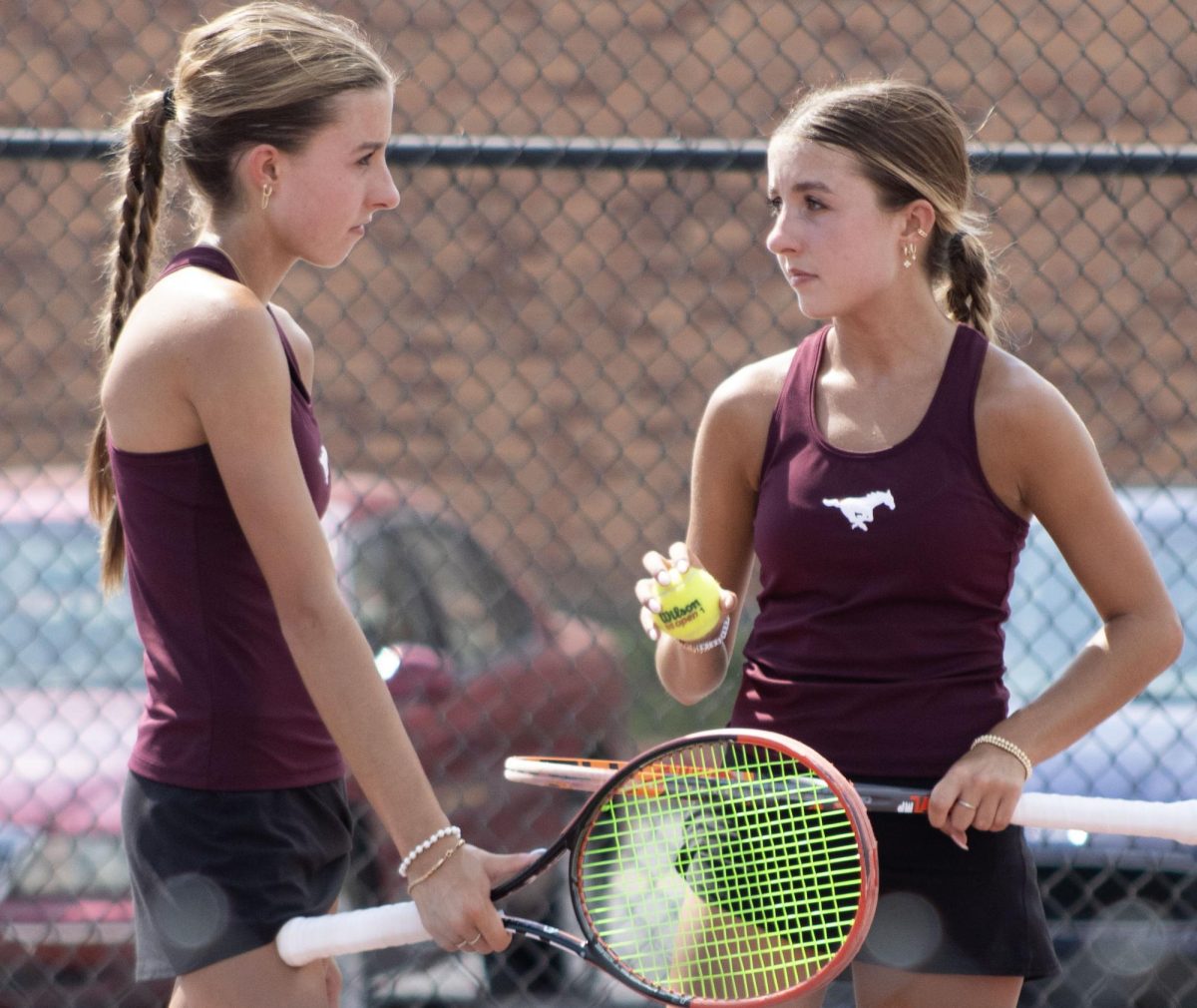 Addison and Mallory Renfro, two thirds of a set of twins on the Central tennis team, discuss strategy during their doubles match at a home meet on Thursday.